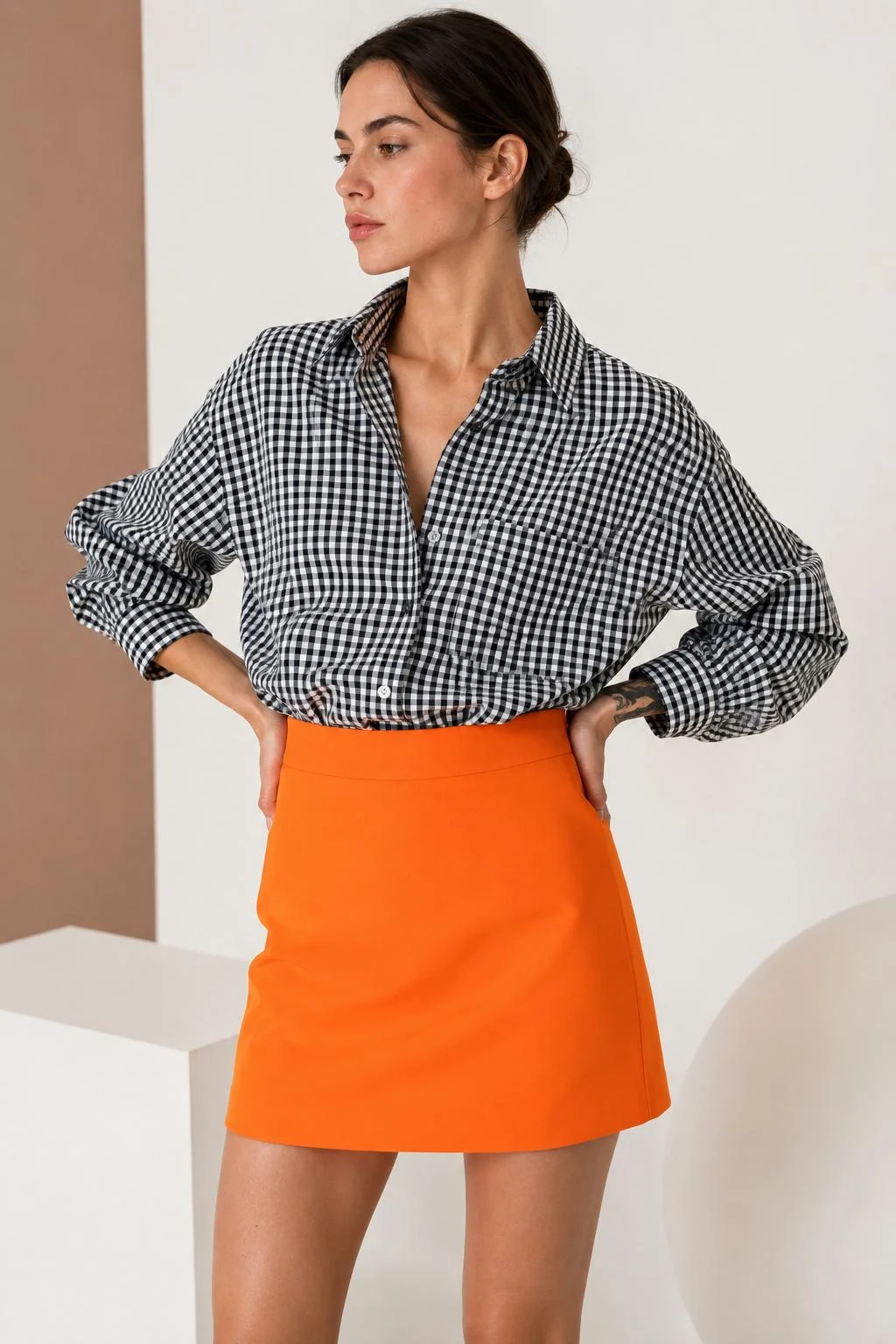 Modella indossa una camicia Vichy bianca e nera con gonna arancio Vestali